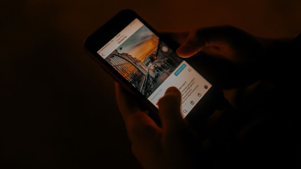 Tangan memegang ponsel sambil membaca informasi di malam hari