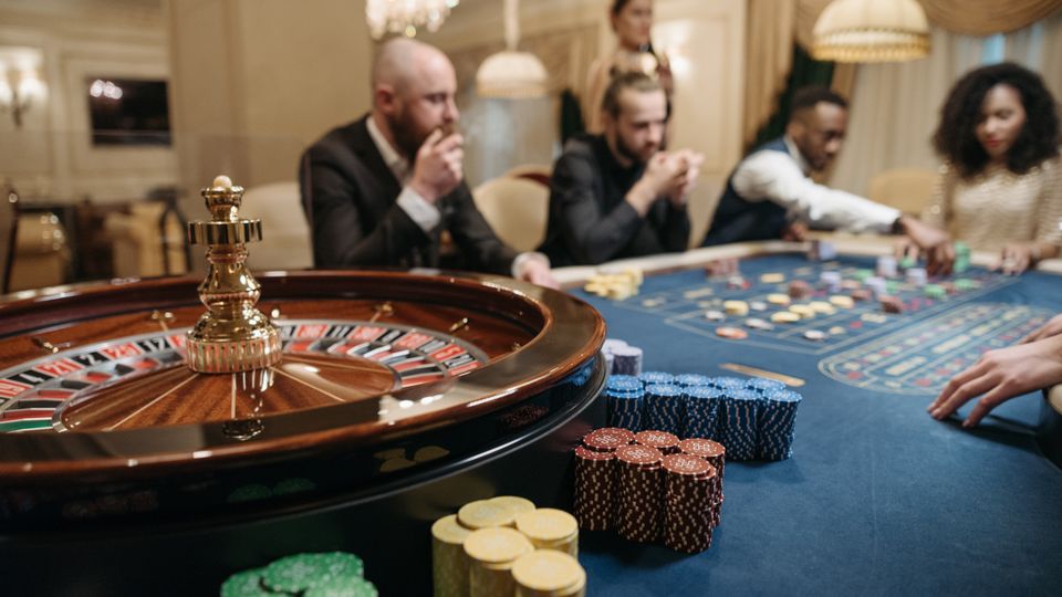 Meja roulette dengan dealer dan pemain di kasino