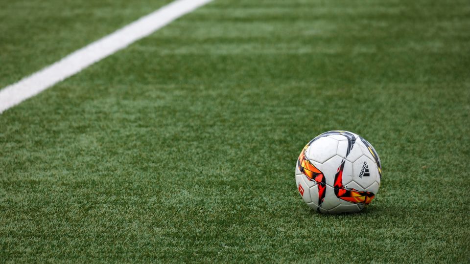 Bola sepak tergeletak di lapangan hijau