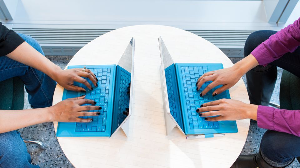 Dua orang bekerja dengan laptop di meja kerja